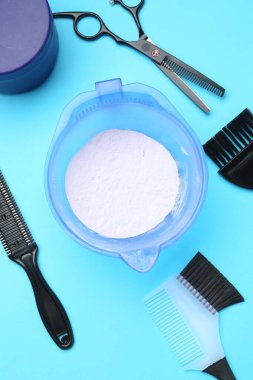 Sarı saçlar ve açık mavi arka planda kuaför aletleri için bakım kozmetik ürünü.