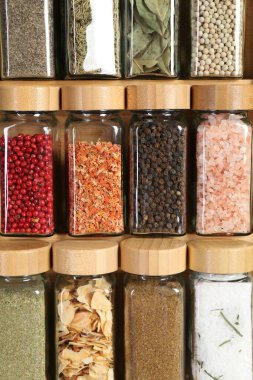 Different spices and jars on wooden background, closeup