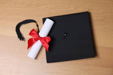 Mezuniyet şapkası ve diploması ahşap masada, düz yatıyordu.