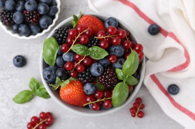 Farklı olgun böğürtlen ve fesleğen yaprakları açık gri desenli masada, düz yatıyordu.