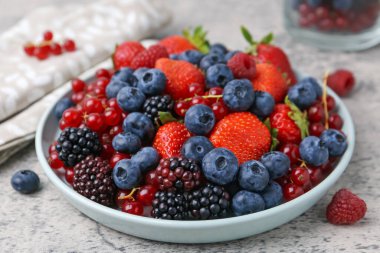 Açık gri dokulu masada farklı olgun meyveler, yakın plan.