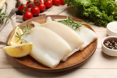 Limonlu ve biberiyeli çiğ mürekkep balıkları açık ahşap masada, yakın plan.