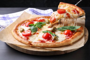 Gri masada peynirli, domatesli ve zeytinli lezzetli bir pizza yemek.