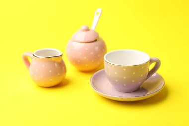Beautiful ceramic tea set for children on yellow background, closeup