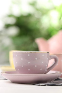 Çocuklar için seramik çay seti. Bulanık arkaplana karşı beyaz ahşap masadaki güzel kupa, metin için yeri olan yakın plan