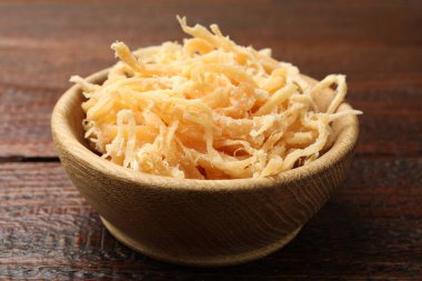 Ahşap masada, tabakta kurutulmuş mürekkep balığı talaşı, yakın plan.