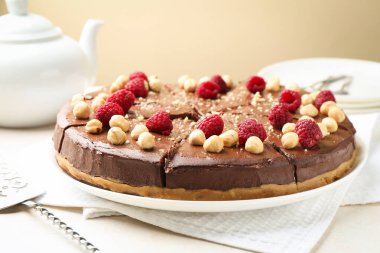 Fındıklı, ahudududulu ve bej masadaki sunuculu lezzetli çikolatalı cheesecake.