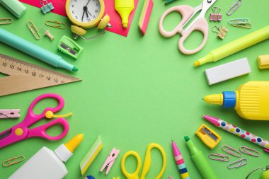 Şişelerdeki yapıştırıcı çerçevesi, çalar saat ve yeşil arka plandaki diğer kırtasiye malzemesi, düz zemin. Metin için boşluk