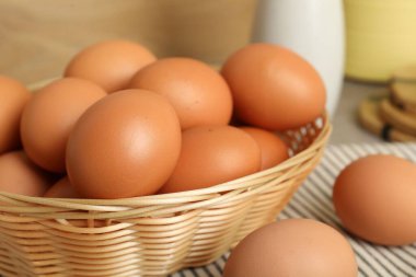 Hasır sepetteki çiğ tavuk yumurtaları masada, yakın plan.