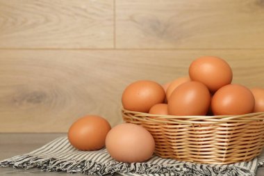Hasır sepetteki çiğ tavuk yumurtaları ahşap tezgahın üstünde, yakın plan. Metin için boşluk