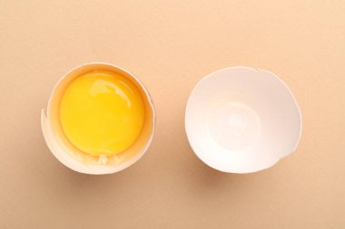 Bej arka planda kırılmış bir tavuk yumurtası.