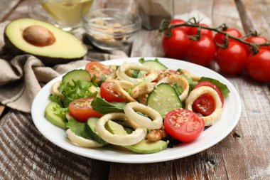 Ahtapot halkaları ve ahşap masa malzemeleriyle nefis bir salata, yakın plan.