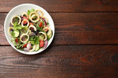 Ahşap masada kalamar halkalı, fındıklı ve sebzeli nefis salata. Metin için boşluk