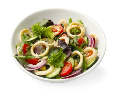 Lezzetli salata, mürekkep balığı halkaları ve beyaz tenceredeki sebzeler.