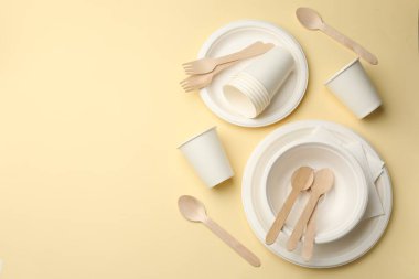 Bej arka planda tek kullanımlık sofra takımı, düz konum. Metin için boşluk