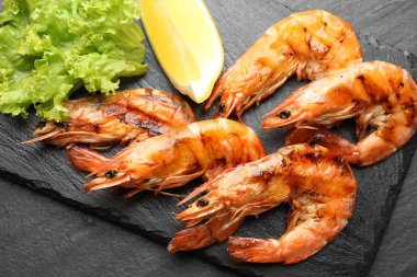 Siyah masada limonlu ve marullu ızgara karides. Lezzetli deniz ürünleri yemeği.