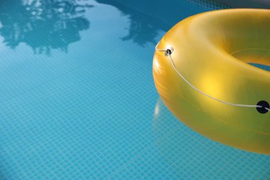 Yellow inflatable ring in swimming pool outdoors, closeup. Space for text