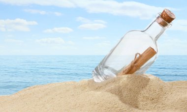 Denize yakın kumda yuvarlanmış mektupla mantar şişesi.
