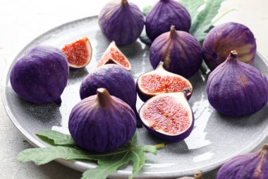 Taze incir ve yeşil yaprak masada, yakın plan.