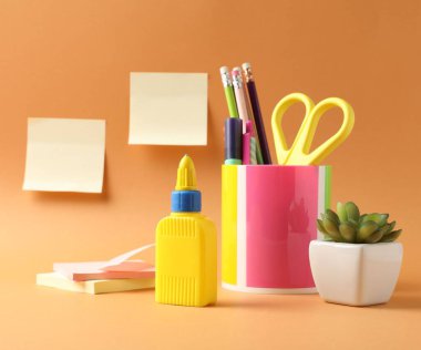 Soluk turuncu arkaplanda yapıştırıcı ve diğer kırtasiye malzemeleri