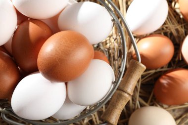 Çiğ tavuk yumurtaları, metal sepetin içinde, saman üzerinde, düz yatıyordu.