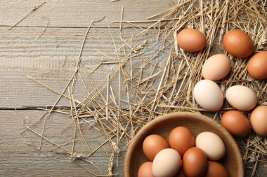 Tabakta çiğ tavuk yumurtası ve ahşap masada saman, düz. Metin için boşluk