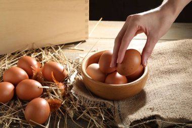 Ahşap masadan çiğ tavuk yumurtası alan kadın, yakın plan.