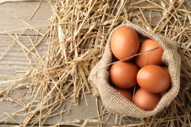 Çuval çuvalında çiğ tavuk yumurtası ve ahşap masada saman, üst manzara. Metin için boşluk
