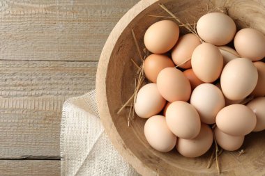 Çiğ tavuk yumurtası ve saman, ahşap masanın üstünde, üst manzara. Metin için boşluk