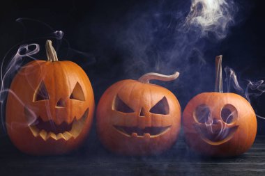 Cadılar Bayramı kutlaması. Kabaklar oyulmuş ürkütücü yüzler ve karanlıkta duman.