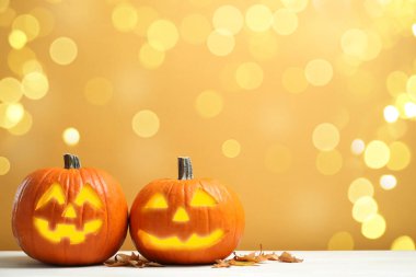 Cadılar bayramı balkabağı fenerleri koyu bej arka planda. Kabaklar oyulmuş tüyler ürpertici yüzler, bokeh etkisi