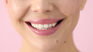 Pembe arka planda güzel dudakları olan gülümseyen kadın, makro manzara.