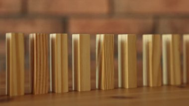 Risk. Tahta bloklar ve insan figürleri domino etkisi altında masaya düşüyor, yakın plan.
