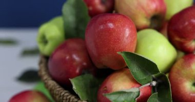 Taze olgun elmalar sepetin içinde beyaz masada, yakın plan. Kamera sağa hareket ediyor