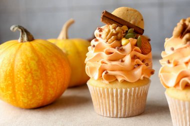 Renkli kremalı, baharatlı, kurabiyeli, fındıklı ve sonbahar desenli kapkekler gri masada, yakın plan.