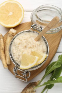 Lezzetli yabanturpu sosu, limon dilimleri ve kökleri beyaz ahşap masa üzerinde, düz uzanmış.