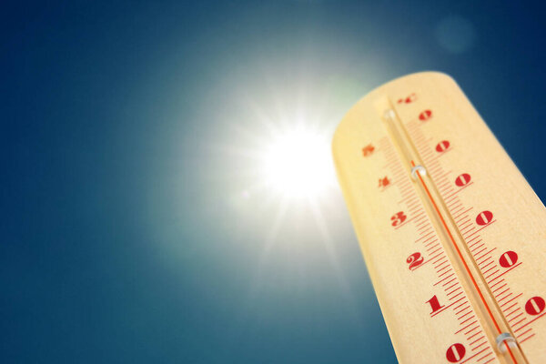 Термометр, показывающий высокую температуру против неба с ярким солнцем. Очень жаркая погода