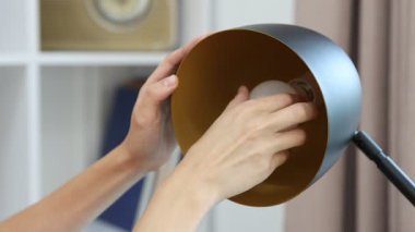 Evde ampulü değiştiren kadın, yakın plan.