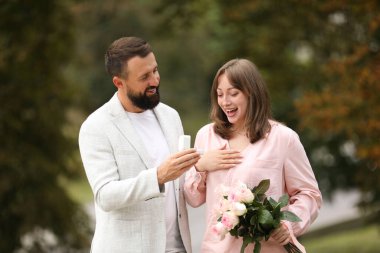 Nişan yüzüklü bir adam kız arkadaşına dışarıda evlenme teklif ediyor.