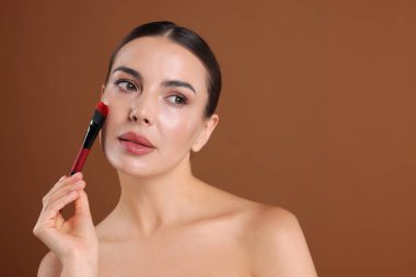 Kahverengi arka planda makyaj fırçası olan güzel kadın, metin için boşluk