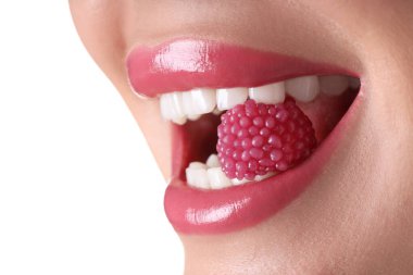 Dudaklarında güzel pembe ruj ve beyaz arka planda ahududu şekeri olan kadın, yakın plan.