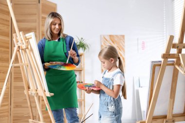 Meslek seçimi. Anne kızına stüdyoda resim yapmayı öğretiyor.