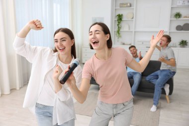 Genç bir kadın evde arkadaşlarıyla karaoke yapıyor, seçici odaklı.