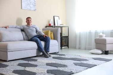 Mutlu genç adam evdeki kanepede dinleniyor, mesaj için yer var.