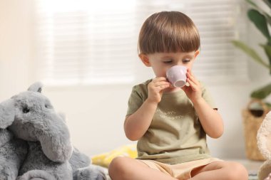 Oyuncak filiyle içeride çay partisi yapan şirin bir çocuk. Metin için boşluk