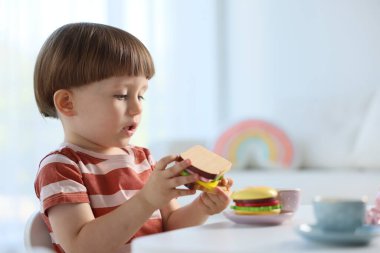 İçerideki masada oyuncak çay takımıyla oynayan şirin bir çocuk. Metin için boşluk