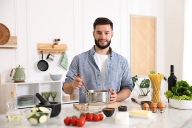 Mutfaktaki masada yemek pişiren gülümseyen adam.