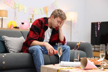 Adam partiden sonra dağınık bir odada kanepede akşamdan kalma.