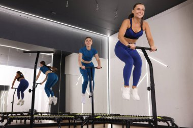 Spor salonundaki mini egzersiz trambolinlerinde zıplayan genç kadınlar, düşük açı.