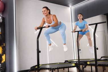 Spor salonundaki mini egzersiz trambolinlerinde zıplayan genç kadınlar, düşük açı.
